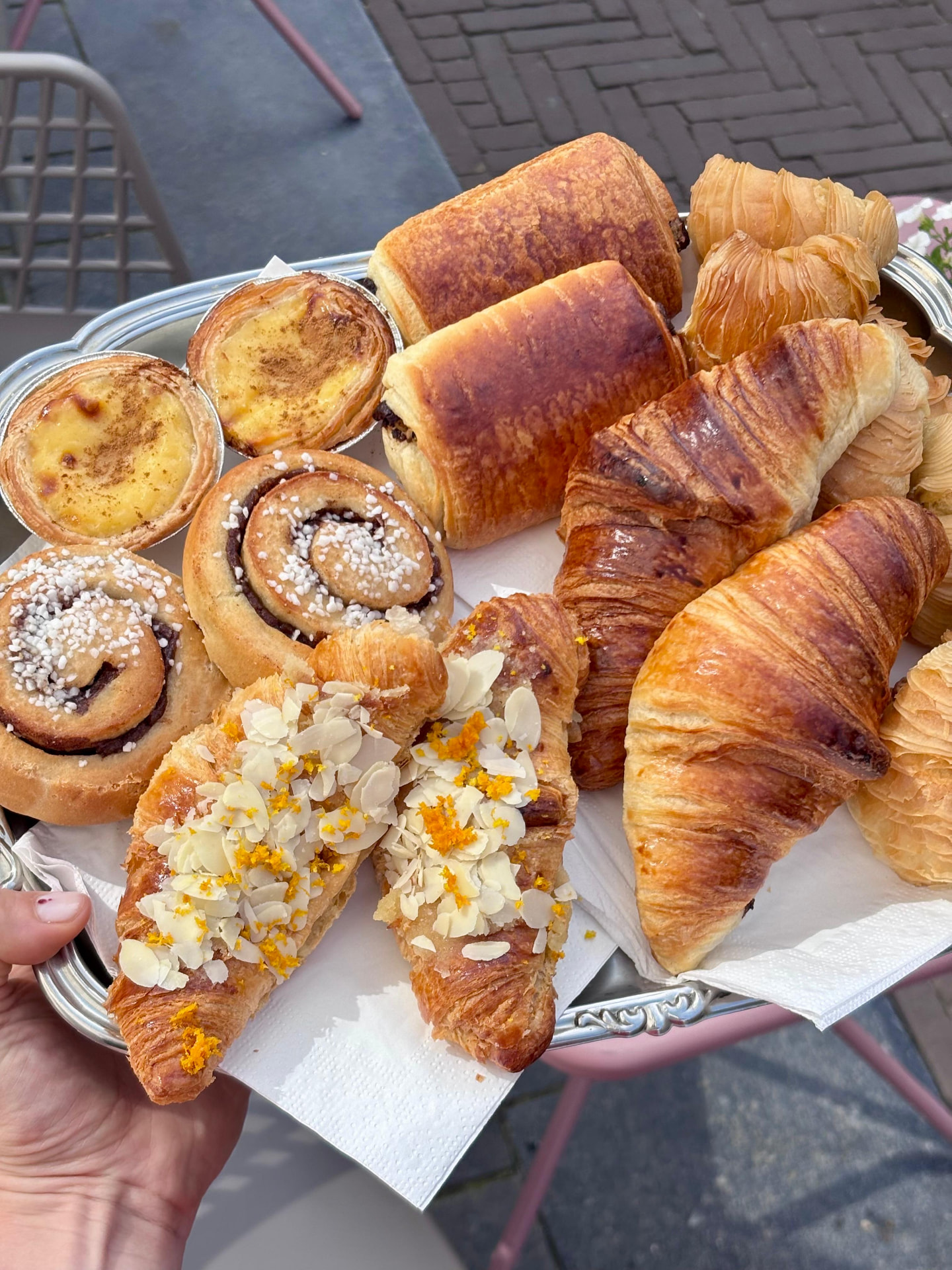 Dienblad met croissants, kaneelbroodjes en gebakjes vastgehouden in de winkel
